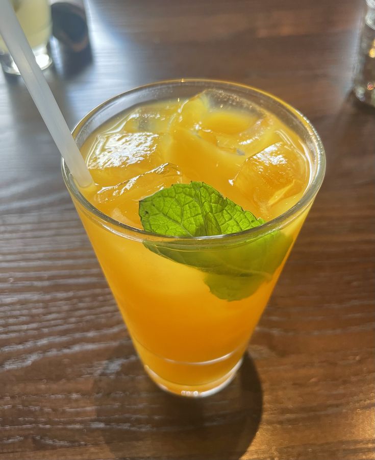 a glass filled with orange juice and mint