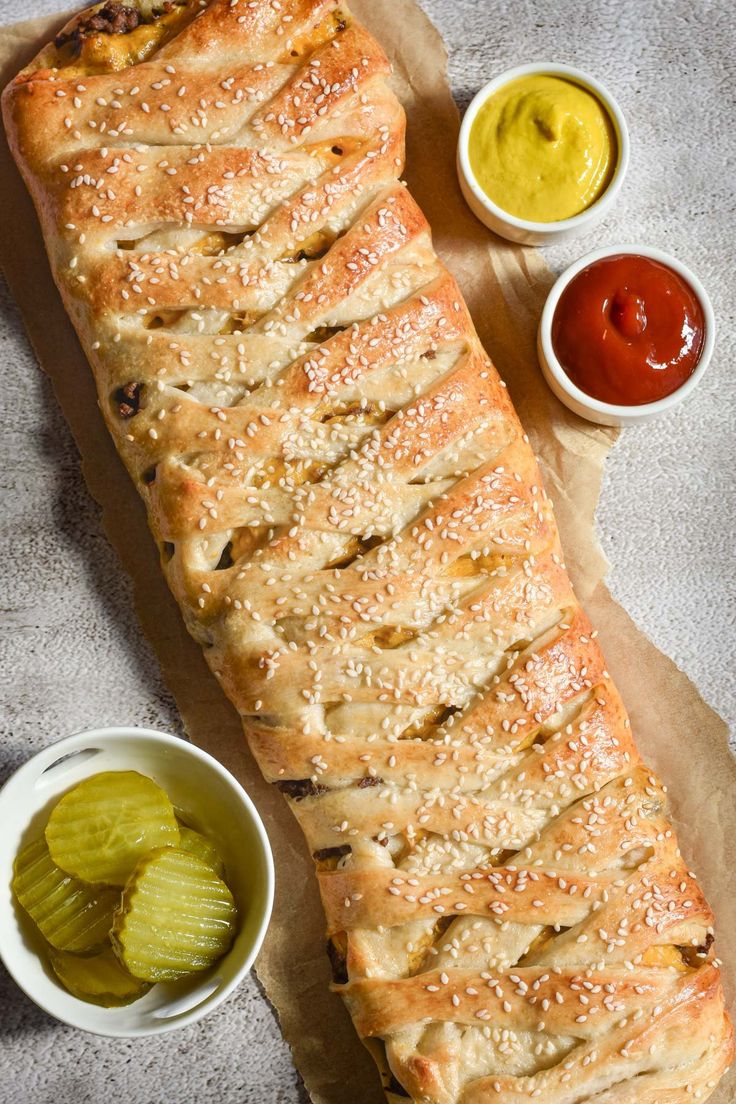 a loaf of bread with some pickles and sauces on the side next to it