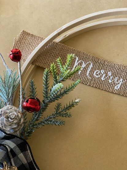 a christmas decoration with pine cones and evergreen needles on a wooden hoop hanging from a wall