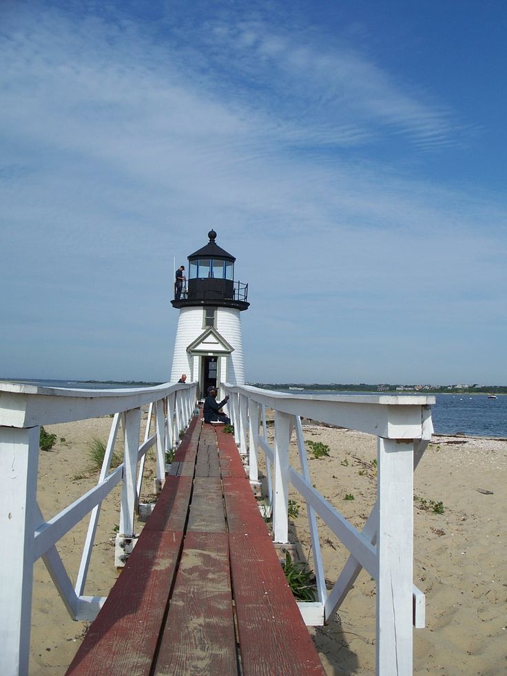 a wooden walkway leading to a light house on the beach