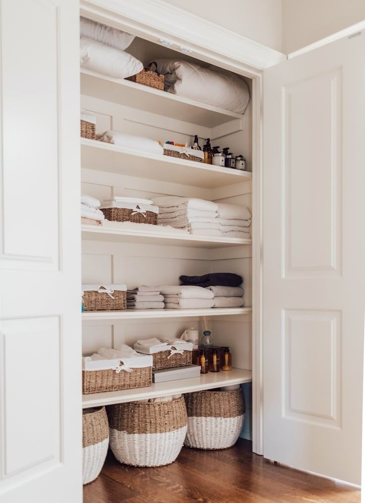 an organized closet with baskets and towels