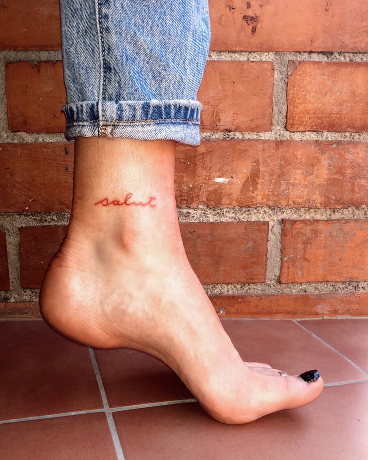 a woman's foot with the word love tattooed on her left ankle and an inscription written in red ink