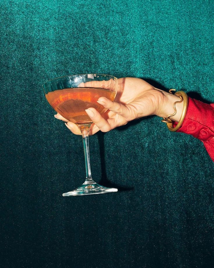 a person holding a wine glass in front of a green carpeted wall and floor