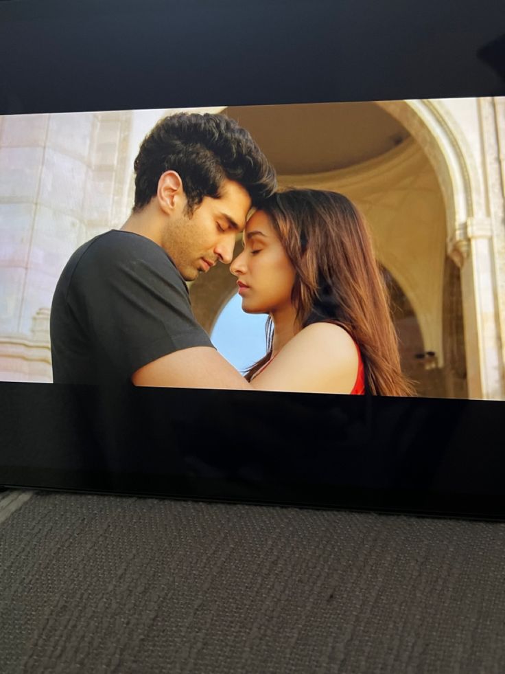 a man and woman are kissing in front of a screen with the image on it