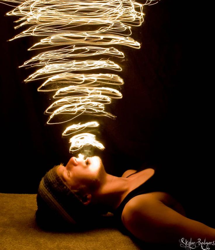 a woman laying on the ground with her head turned upside down and light streaks coming out of her face