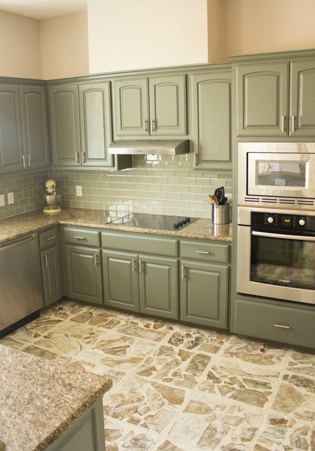 a kitchen with green cabinets and marble counter tops