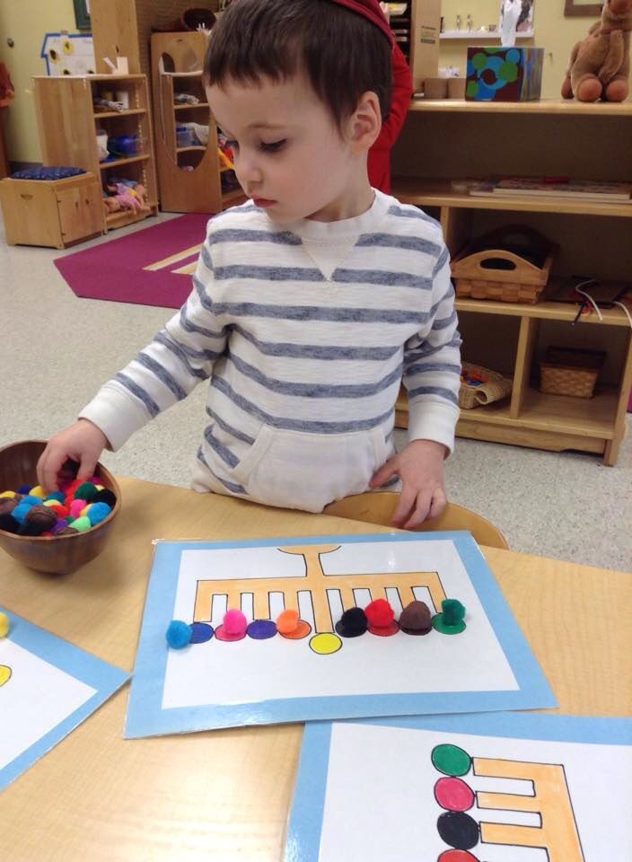 a young boy sitting at a table playing with some sort of beads