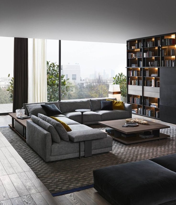 a modern living room with black and white furniture in the center, bookshelves on the wall