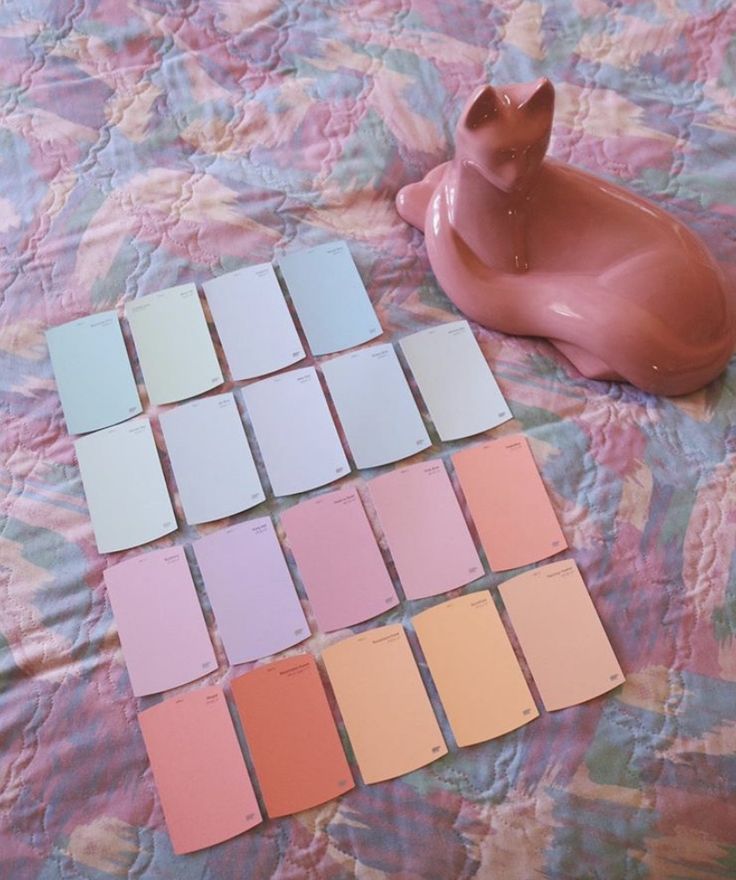 a pink pig figurine sitting on top of a bed next to color swatches