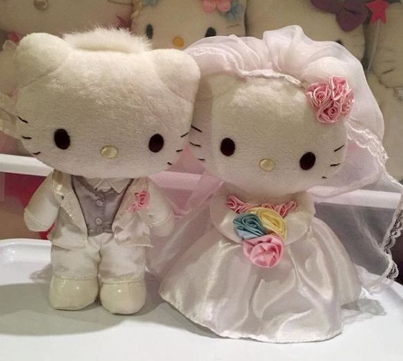 two hello kitty dolls dressed up in wedding attire sitting next to each other on a table