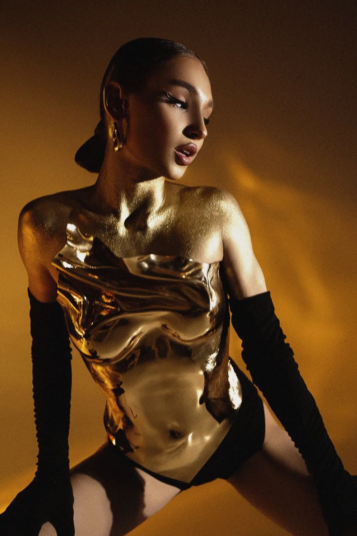 a woman in gold bodysuit and black gloves