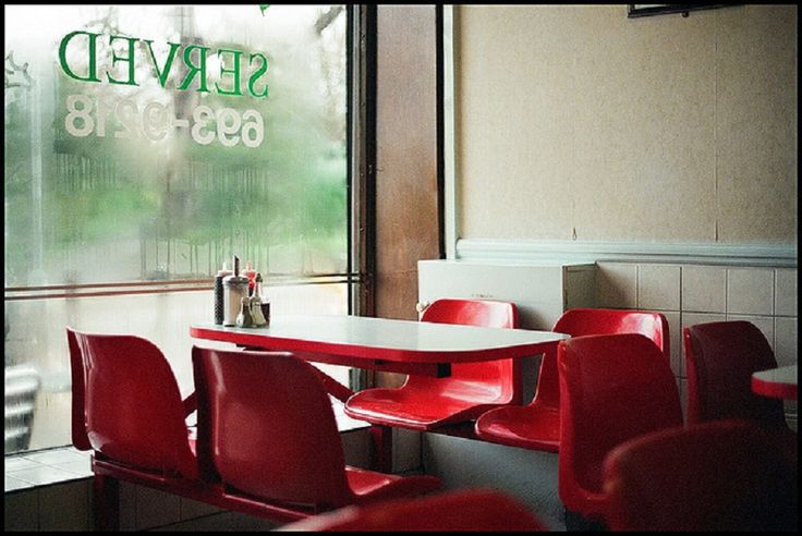 a restaurant with red chairs and a white table in front of a window that reads served