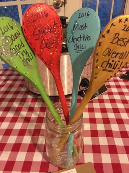 five spoons with writing on them sitting in a jar at a table that has a red and white checkered tablecloth