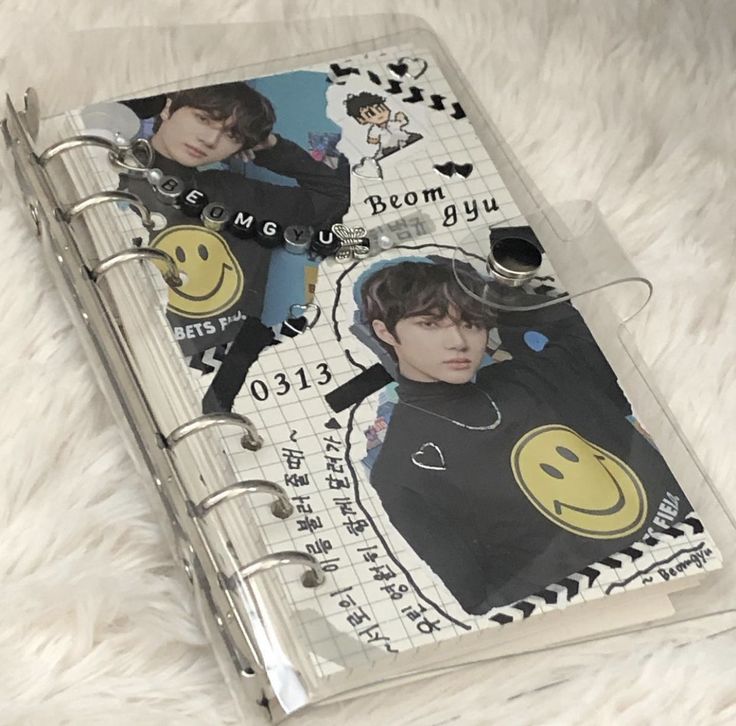 a notebook with an emo smiley face on the front and back cover is laying on a white furnishing