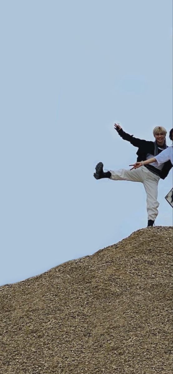 two men are standing on top of a hill and one is throwing a frisbee