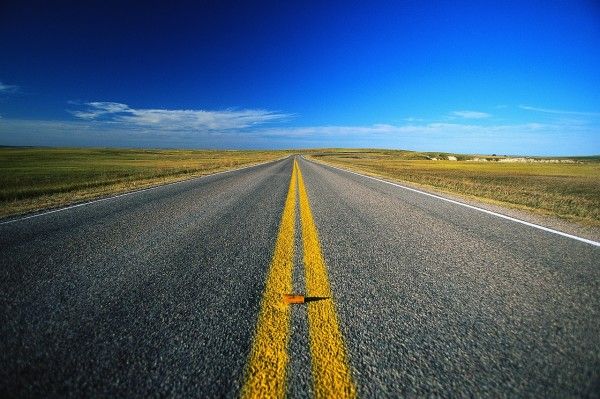 an empty road in the middle of nowhere with a single orange arrow painted on it