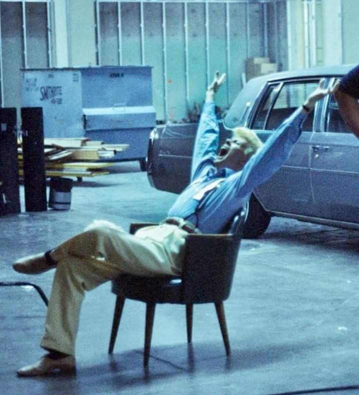 a man laying on top of a chair next to a car