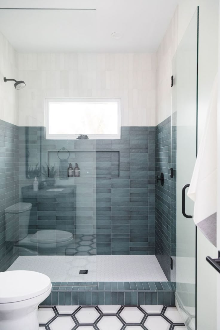 a white toilet sitting in a bathroom next to a walk in shower and tiled floor