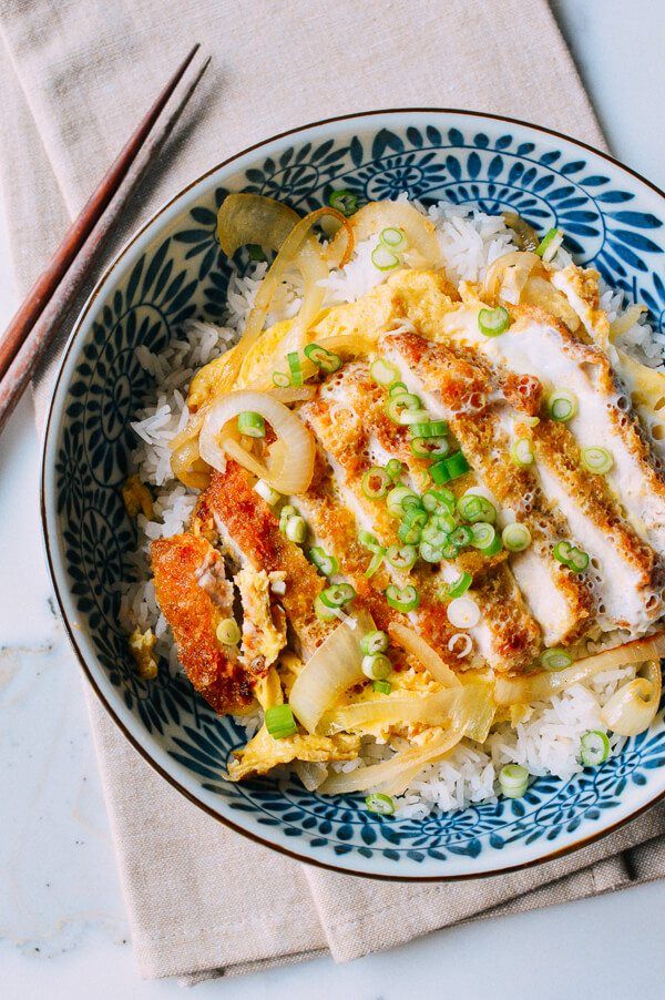 a blue and white bowl filled with food next to chopsticks on top of a table