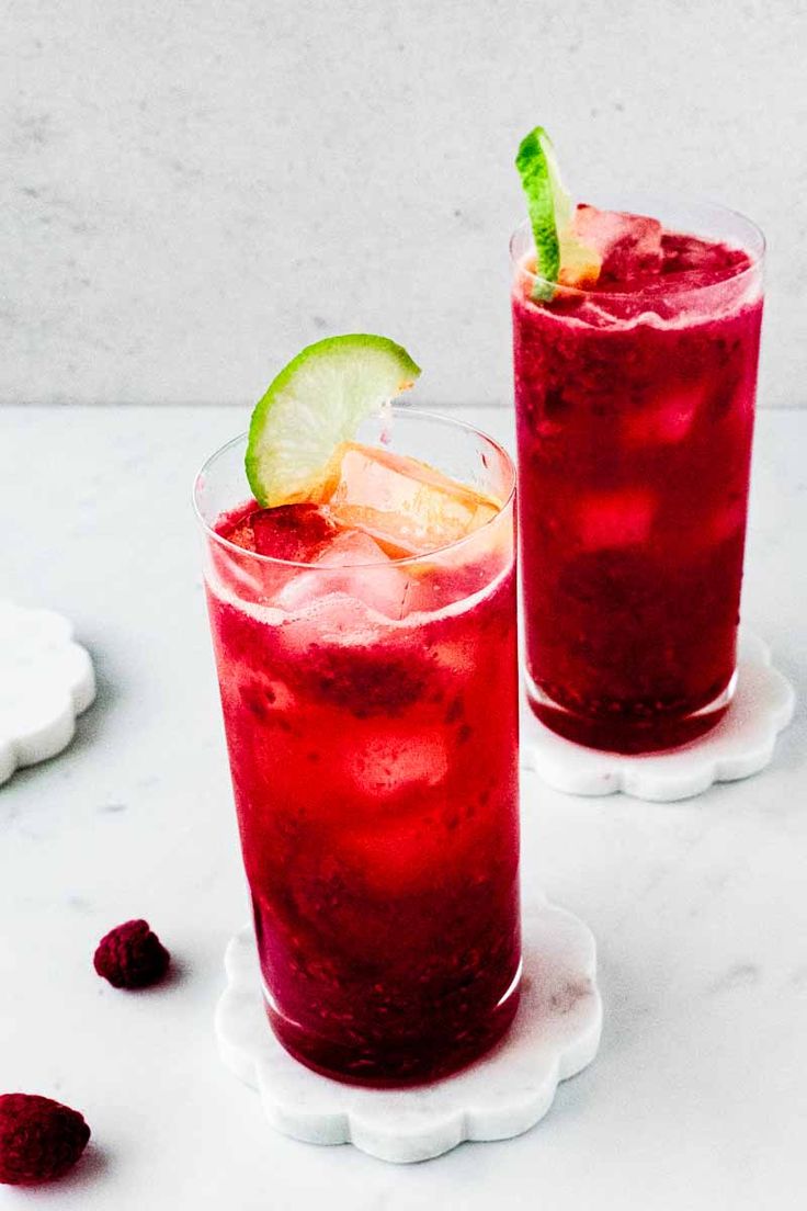 two glasses filled with raspberry lemonade margaritas on top of a white plate