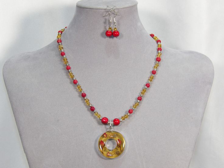 Simply beautiful!  A round sterling silver pendant with pressed flowers is the centerpiece of the necklace.   The pendant is 1 1/4 inches in diameter and features flowers in resin encased in sterling silver.  The necklace has red bamboo coral and yellow glass beads, complimenting the flowers in the pendant.  The necklace measures 20 inches in length and has a toggle closure. The matching earrings feature the the bamboo coral and yellow glass beads found in the necklace.  The earrings measure 3/4 Red Circular Jewelry For Gifts, Red Circle Jewelry For Gift, Nickel-free Round Amber Necklaces, Nickel-free Yellow Round Pendant Jewelry, Silver Czech Glass Round Necklace, Orange Circular Jewelry As A Gift, Orange Circular Jewelry Gift, Round Silver Czech Glass Necklace, Flowers In Resin