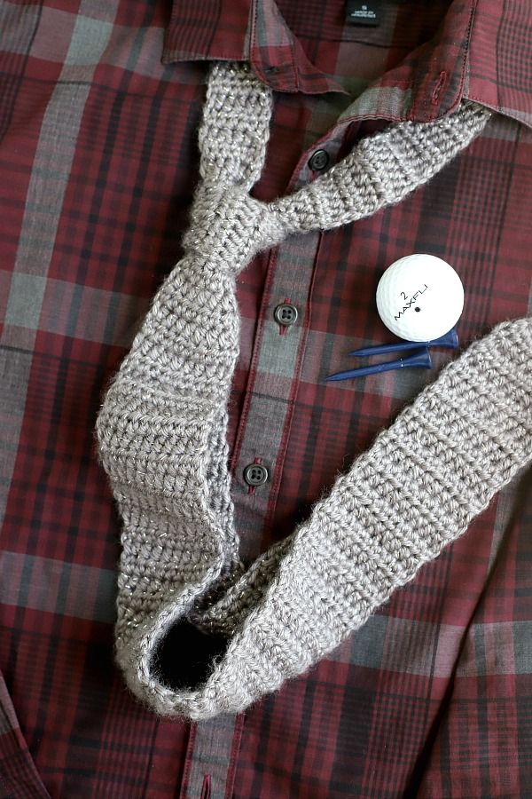 a button up shirt with a knitted neck tie next to an empty pocketed sweater