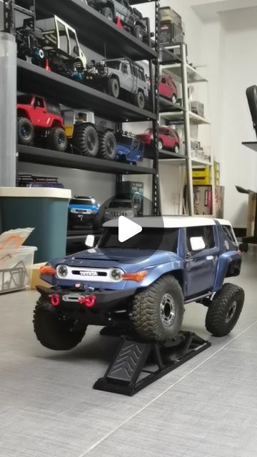 a blue truck is parked in a room with shelves full of toy cars and trucks