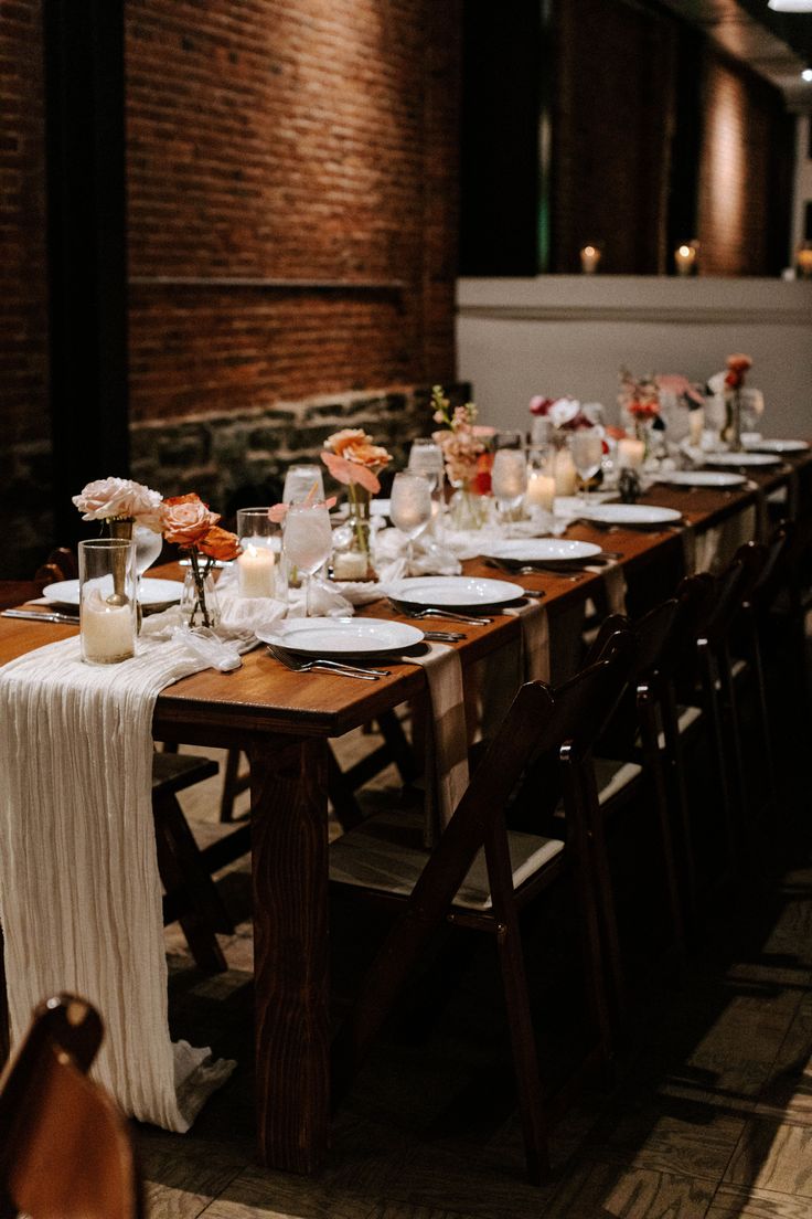 a long table is set with plates and candles