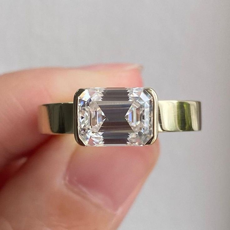 a person is holding an engagement ring with two stones on the front and back of it