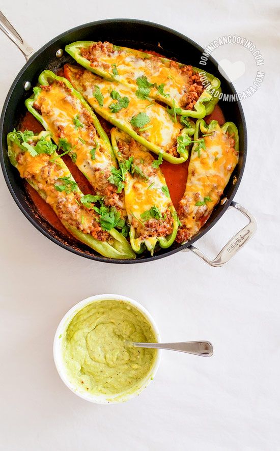 an overhead view of some stuffed peppers and guacamole in a skillet