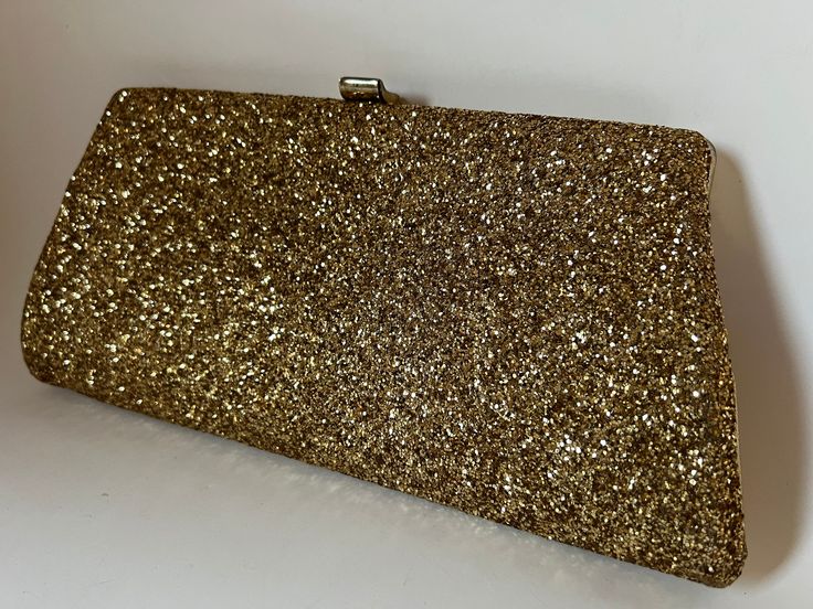 "This fabulous A-line clutch is encrusted in gold glitter to make a real statement! The bag tapers from 9\" wide at the top to 11\" wide at the base. The back is covered with leather-grained metallic-gold vinyl. Exposed square brass-color frame and simple rectangular tip-up clasp. The interior is lined in black nylon and has a wrist-length convertible curb chain handle that can be used or tucked inside. Excluding clasp and chain, the bag measures 5 1/4\" high x 1 1/4\" deep. With the chain fully Rectangular Gold Glitter Clutch, Black Evening Bag, Beaded Evening Bags, Color Frame, Gold Vinyl, Black Nylon, Curb Chain, Black Nylons, Brass Color