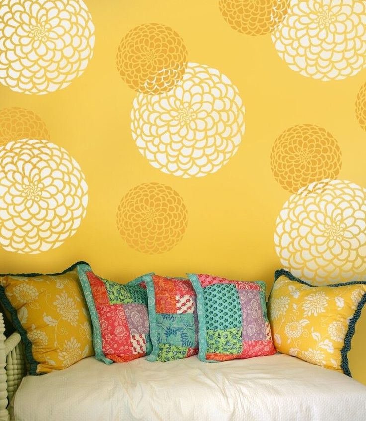 a white couch sitting in front of a yellow wall with decorative circles on the wall