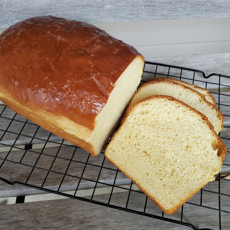 a loaf of bread sitting on top of a metal rack next to a slice of bread