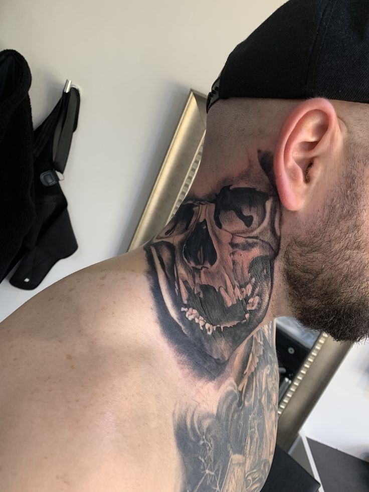 a man with a skull tattoo on his neck is looking at the camera while wearing a baseball cap