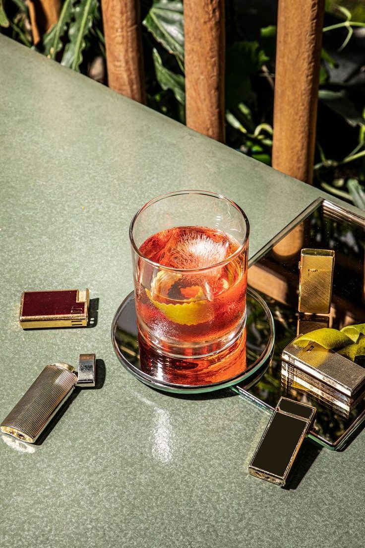 a glass filled with liquid sitting on top of a table next to two lighters