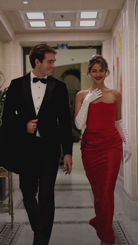 a man and woman in formal wear walking down a hallway