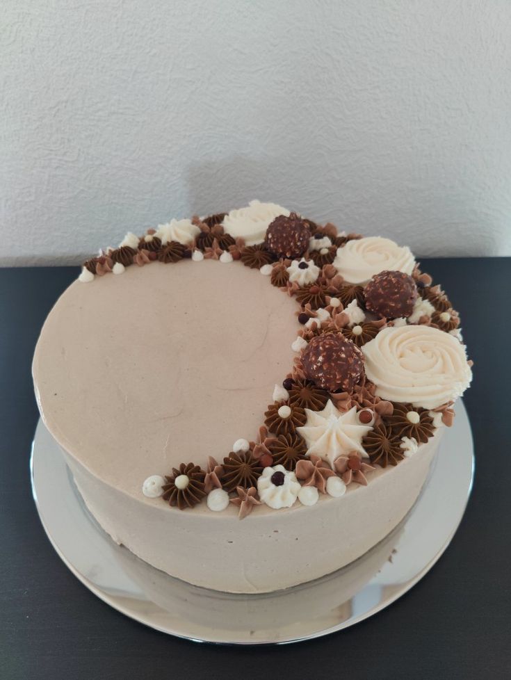 a cake with white frosting and brown flowers on the top is sitting on a plate