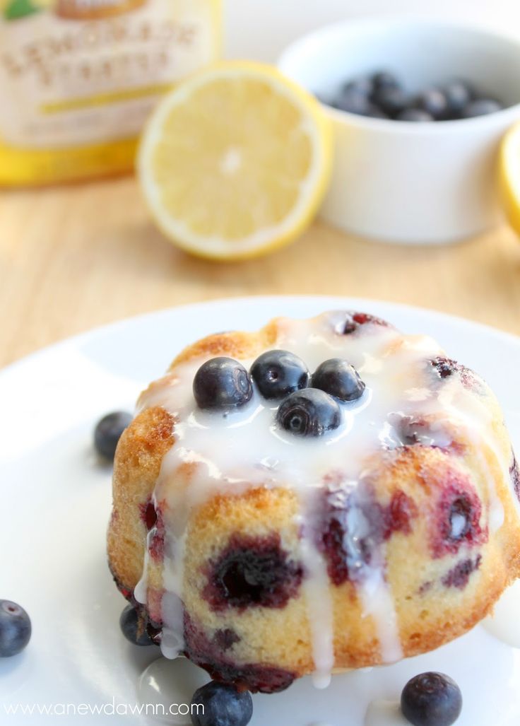 a blueberry bunt cake on a white plate with lemons and blueberries