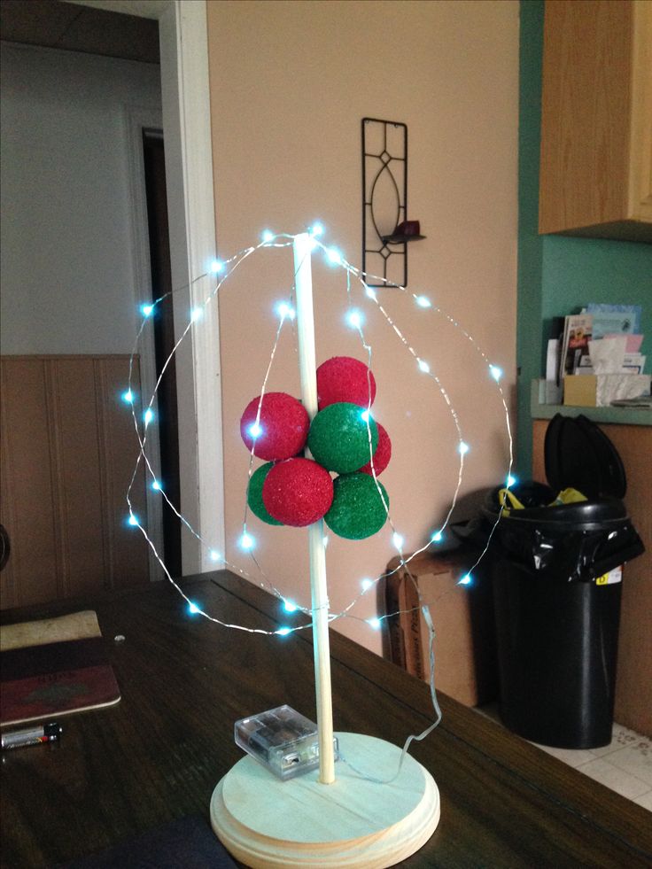 a christmas decoration on top of a wooden table in a living room with lights around it