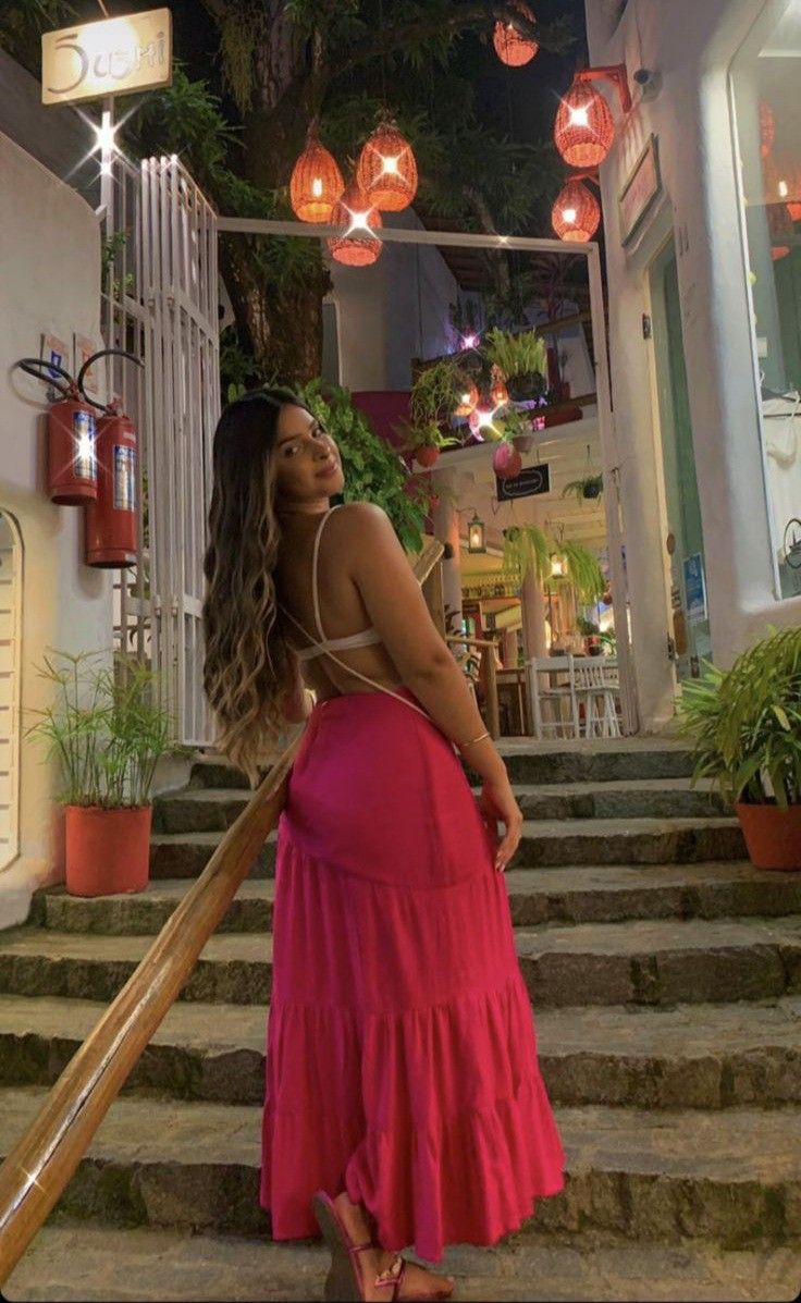 a woman in a pink dress is standing on stairs