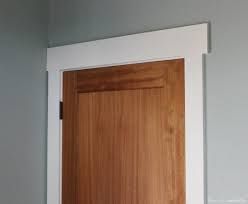 a wooden door in the corner of a room with gray walls and white trim on it