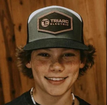 a young boy wearing a hat with the word trapc electric on it's side