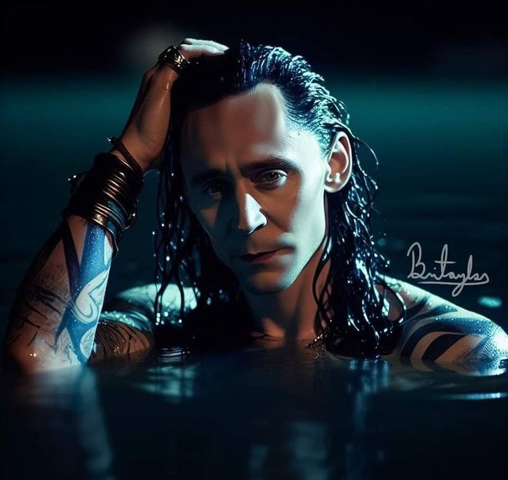 a man with long black hair and tattoos in the water looking at the camera while holding his hand on his head