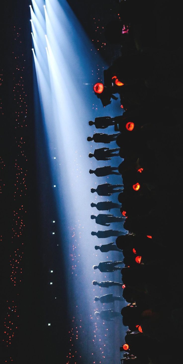 a group of people standing on top of a stage under a spotlight filled with lights