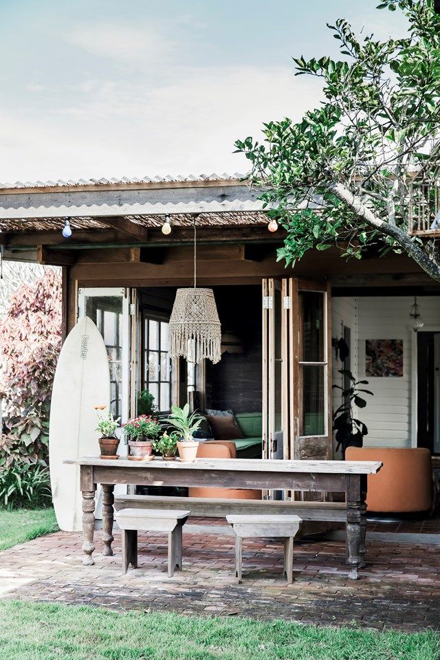 a wooden table sitting on top of a lush green field next to a surfboard