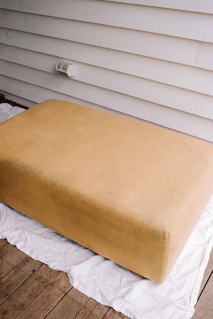 a large brown cushion sitting on top of a wooden floor next to a white house