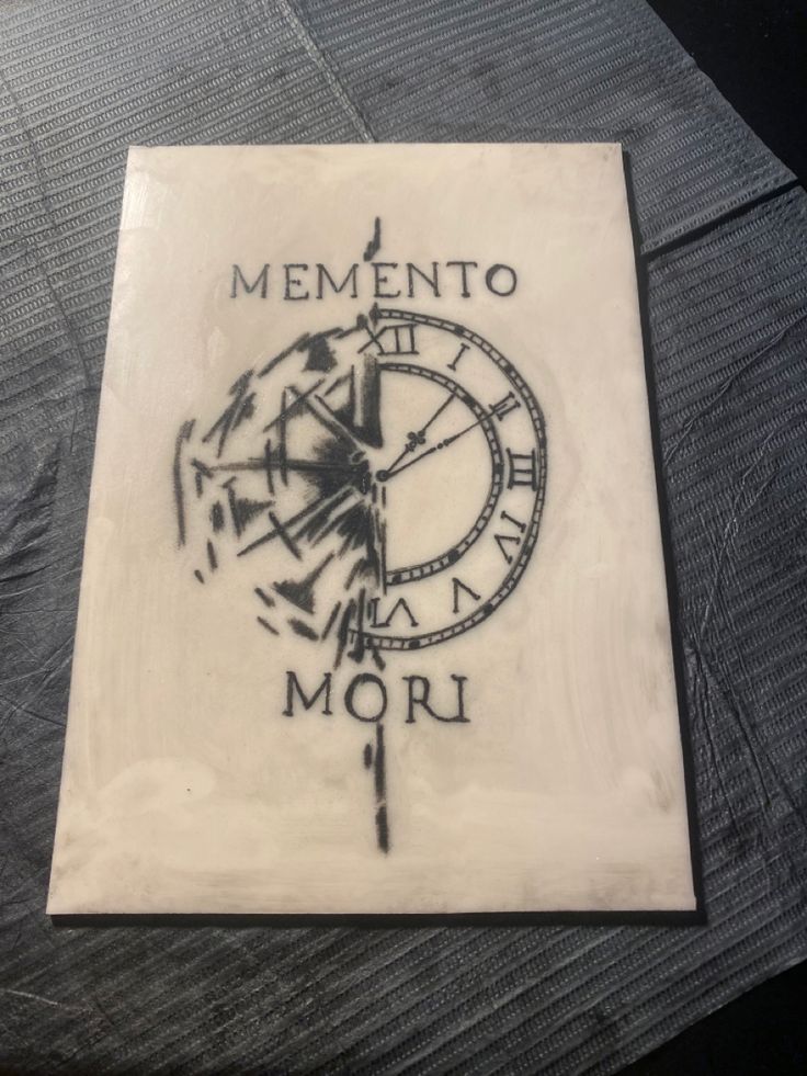 a clock with the words mementoo and roman numerals written on it