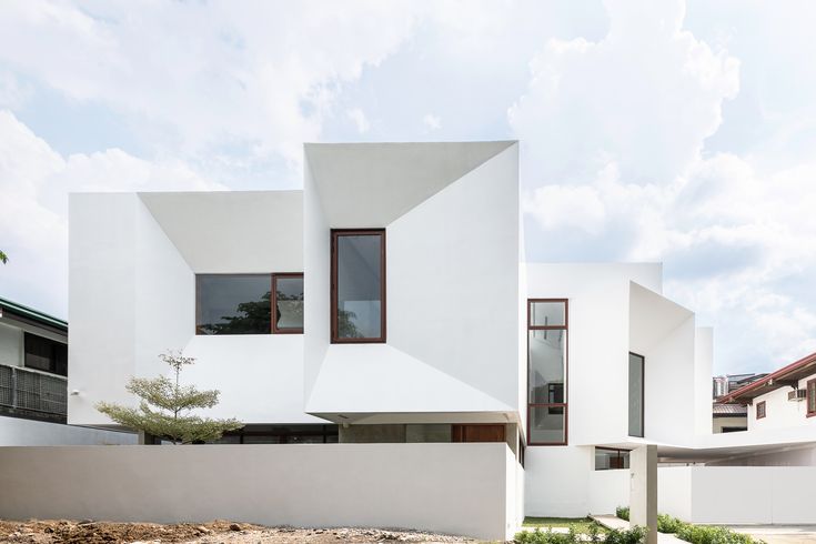 a modern house with white walls and windows on the outside, surrounded by grass and trees