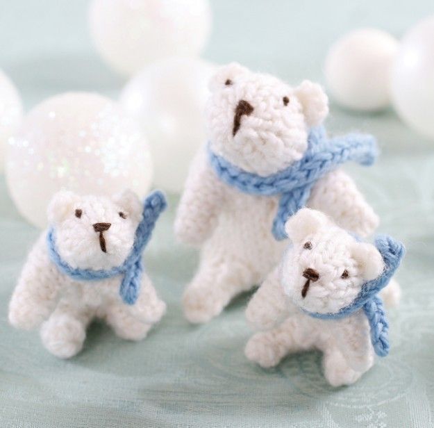 three small white teddy bears with blue scarves