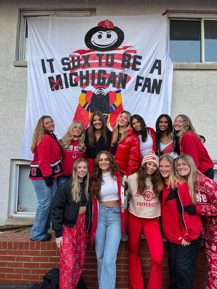 a group of young women standing next to each other in front of a sign that says it's so big like a michigan fan